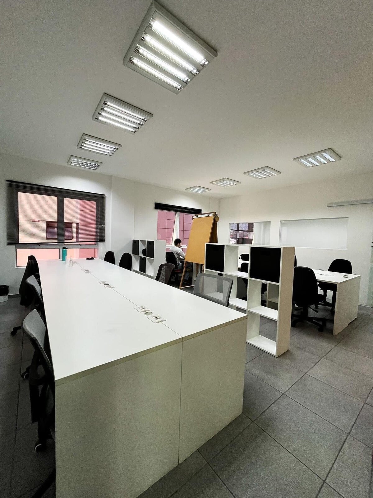 Espaço de trabalho da equipe com mesas amplas e janelas